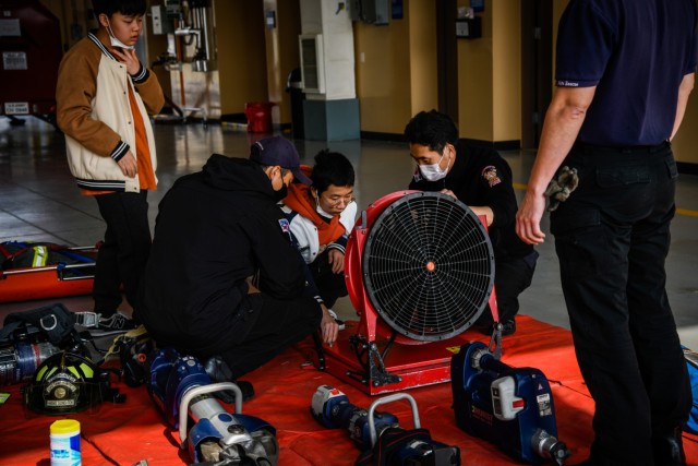 Seongjoo Kim (standing) and Seongsoo Kim (kneeling), both students at Camp Humphreys Middle School, take turns operating the firefighter ventilation fan during the Learning Impaired Moderate to Severe program’s trip to Fire Station 4 on Camp...