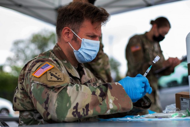 U.S. Army Sgt. Joshua Milewski, a member of the Vaccine Equity Task Force’s Mobile Vaccination Support Team and the Maryland National Guard, prepares a COVID-19 vaccine to be administered in an Aldi’s parking lot in Takoma Park, Maryland, Oct....