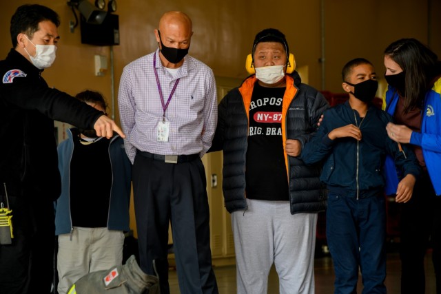 Antiny White (center left) and Chrissy Davis (right), both paraprofessionals at Humphreys Middle School, listen with their students, Landen Yoo (middle) and Jordan Ralls (middle right), as Hwang Song-tok, a firefighter on Camp Humphreys, South...