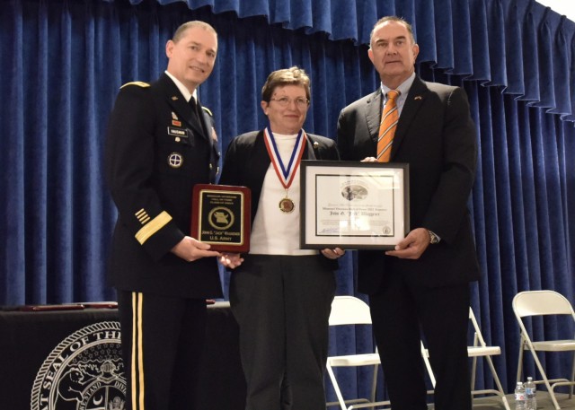 Mary Waggener accepts her father’s induction into the Missouri Veterans Hall of Fame from Missouri Lt. Gov. Mike Kehoe (right) and Missouri National Guard Director of the Joint Staff, Brig. Gen. Charles Hausman, at a ceremony Friday in the...
