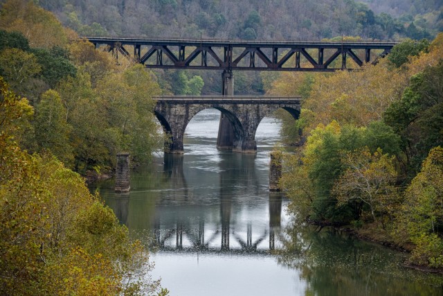 A stone archway and a railroad crossing over the Conemaugh River viewed from the top of the lake’s dam in Saltsburg, Pennsylvania, Oct. 22, 2021. These structures offer a glimpse back in history, which tell the story of how old railroads had to...