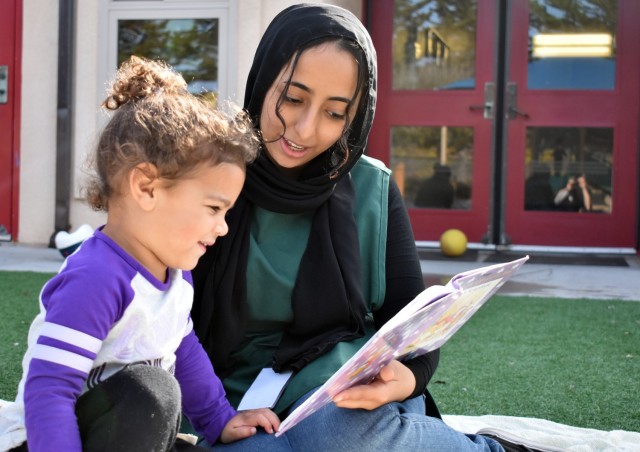 Maha Ahmed, a child care provider, reads a book to Reilly Estevan, 2, at the Child Development Center at Ord Military Community, Nov. 4.