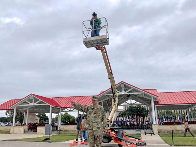 The U.S. Army Medical Center of Excellence, or MEDCoE, hosted the 32d Medical Brigade Change of Command Ceremony November 11, 2021 on the MacArthur Parade Field, Joint Base San Antonio-Fort Sam Houston, Texas. The ceremony was preceded by a historic photo with over 4,000 MEDCoE Soldiers and Civilians in formation on the field. Pictured: Jose Rodriguez, U.S. Army Medical Center of Excellence (MEDCoE) Public Affairs perched on a lift to take the panoramic photo while Sgt. Maj. Ronald Gebhardt, G3 Command Sergeant Major, directs the formation for the group photo. 