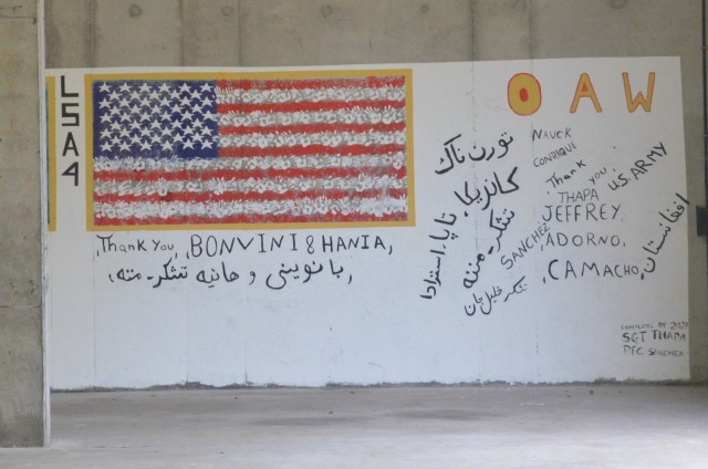 A mural was painted by the travelers in living support area 4 on Rhine Ordnance Barracks during Operation Allies Refuge. According to a translator, the writing in Pashtu has people’s names, Afghanistan, several thank you’s and good-byes. The white stripes on the flag are made up of handprints.