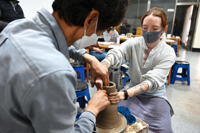 Margaret Manning, spouse of 2nd Lt. Keene Manning, from 304th Expeditionary Signal Battalion, 1st Signal Brigade, creates a pot with the assistance of potter Kim Sang-lok during a cultural ceramics tour Nov. 15, 2021, in Yeoju, South Korea. (Photo by Monica K. Guthrie)