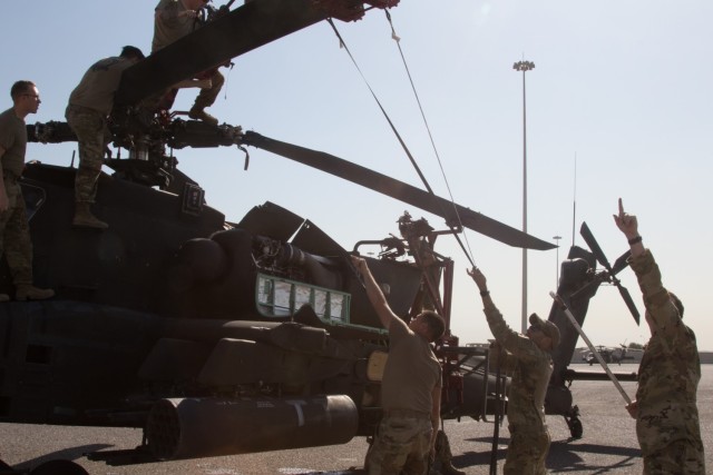 Attack helicopter repairers and AH-64E Apache pilots assigned to the Fort Bragg, North Carolina, based 82nd Combat Aviation Brigade, 82nd Airborne Division, work as a team to fold a rotor blade of an AH-64E Apache helicopter at the Port of Shuaiba, Kuwait, Nov. 10, 2021. The Aberdeen Proving Ground, Maryland, based 1100th Theater Aviation Sustainment Maintenance Group oversaw the preparations for the retrograde of more than 30 aircraft assigned to the 82nd CAB from Nov. 7-12. The Soldiers and aircraft were deployed to Afghanistan to support base closures and the U.S. military’s exit from the Hamid Karzai International Airport in Kabul.