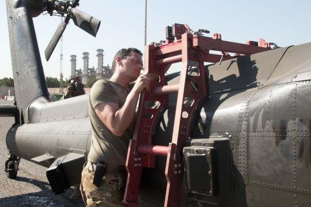 Spc. Nicholas J. Chavez, an attack helicopter repairer assigned to the Fort Bragg, North Carolina, based 82nd Combat Aviation Brigade, 82nd Airborne Division, affixes a brace to the tail of an AH-64E Apache helicopter at the Port of Shuaiba, Kuwait, Nov. 10, 2021. The Aberdeen Proving Ground, Maryland, based 1100th Theater Aviation Sustainment Maintenance Group oversaw the preparations for the retrograde of more than 30 aircraft assigned to the 82nd CAB from Nov. 7-12. Chavez and his fellow Soldiers were deployed to Afghanistan to support base closures and the U.S. military’s exit from the Hamid Karzai International Airport in Kabul.
