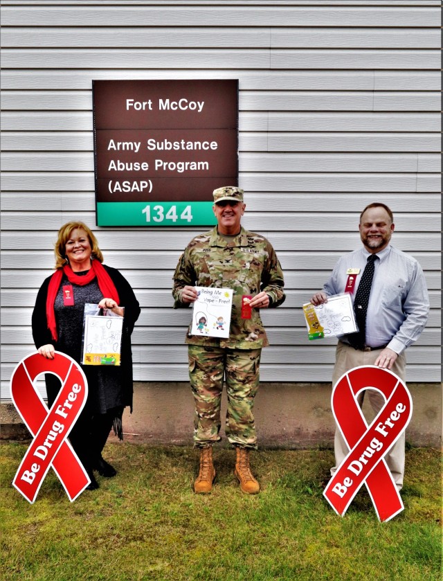 Michelle Bourman, Army Substance Abuse Program specialist; Garrison Commander Col. Michael Poss; and Terry Rogalla, Employee Assistance Program counselor and Suicide Prevention program manager, show their support Oct. 28, 2021, for National Red...