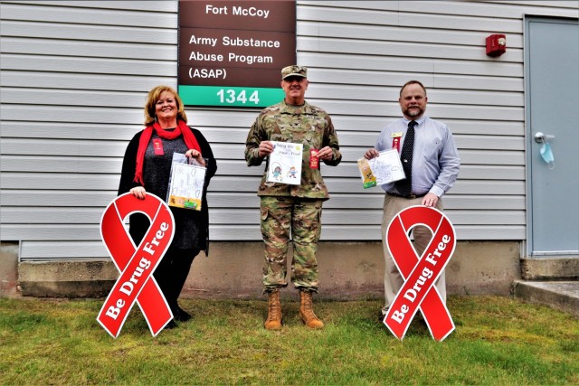Michelle Bourman, Army Substance Abuse Program specialist; Garrison Commander Col. Michael Poss; and Terry Rogalla, Employee Assistance Program counselor and Suicide Prevention program manager, show their support Oct. 28, 2021, for National Red...
