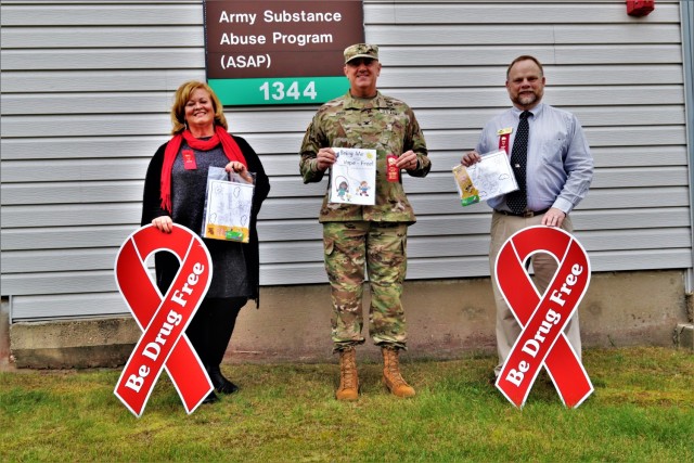 Michelle Bourman, Army Substance Abuse Program specialist; Garrison Commander Col. Michael Poss; and Terry Rogalla, Employee Assistance Program counselor and Suicide Prevention program manager, show their support Oct. 28, 2021, for National Red...