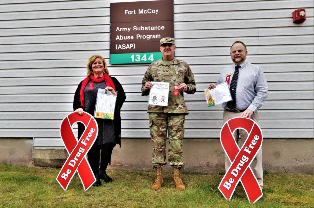 Michelle Bourman, Army Substance Abuse Program specialist; Garrison Commander Col. Michael Poss; and Terry Rogalla, Employee Assistance Program counselor and Suicide Prevention program manager, show their support Oct. 28, 2021, for National Red...