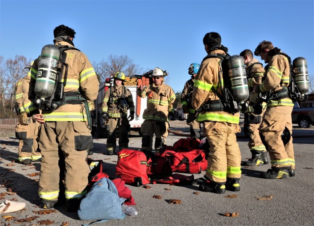Four students get their protective fire gear on and receive instructions as they prepare for car fire training Nov. 19, 2021.