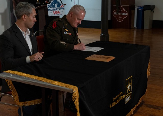 U.S. Army North Commanding General Lt. Gen. John R. Evans, Jr., right, signs the ceremonial agreement reaffirming the commitment between the city of San Antonio and the United States Army for the Partnership for Youth Success (PaYS) Program by signing a memorandum of agreement alongside city of San Antonio, Mayor Ron Nirenberg, left, at the Plaza de Armas Gallery, San Antonio, Texas, Nov. 19, 2021. The U.S. Army PaYS Program guarantees Soldiers and ROTC cadets five job interviews and possible employment with the city of San Antonio government after their service in the U.S. Army.
