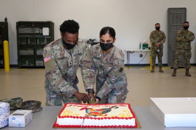Spc. Simeon Hardy, left, and Spc. Divya Kharbanda, right, assigned to the "Maintain Battalion,: 703rd Brigade Support Battalion, 2nd Armor Brigade Combat Team, 3rd Infantry Division, cut the ceremonial cake after the opening ceremony of the 2nd ABCT supply support activity facility at Fort Stewart, Georgia, Nov. 9, 2021. The new SSA facility brings to bear modernized systems and processes to provide all items necessary to equip, maintain and sustain 2nd ABCT's modernization effort and supports the Division's glide path to become the most modernized division in the U.S. Army by summer of 2023. (U.S. Army photo by Sgt. Trenton Lowery)