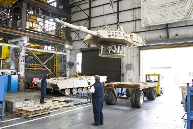 The M1A1/M1A2 Abrams Main Battle Tank has become a staple in the Combat Vehicle Repair Facility. Two members of the workforce can be seen moving a turret for re-installation in the hull.