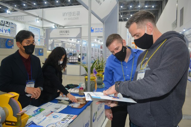 Capt. Chris Benson, Current Operations officer in charge, Operations (left), and Chief Warrant Officer 3, Ryan Chaney, senior ground maintenance warrant officer, Support Operations, peruse literature at the Daegu Machinery Expo, Nov. 19.