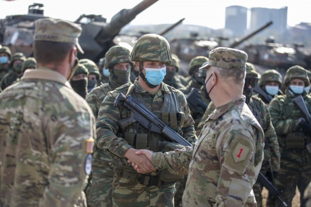 U.S. Army Col. Brian McCarthy (right), commander of 1st Armored Brigade Combat Team, 1st Infantry Division, congratulates a soldier with the Hellenic Army during the closing ceremony for Olympic Cooperation 2021 at Petrochori Range, Triantafyllides Camp, Greece, Nov. 16, 2021. “Any opportunity we get to work with an ally, we get to learn a little bit more about the tactics, techniques and procedures that each of us use,” McCarthy said. 