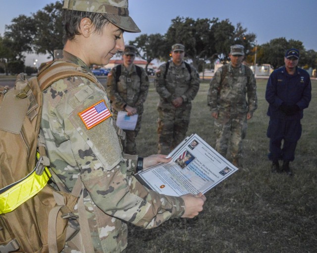 Army Capt. Leanne Bishara, clinical psychology intern, reads the biography of a fallen service member during a memorial march at Joint Base San Antonio-Fort Sam Houston, Nov. 19, 2021. The 2nd Annual Memorial March honored Army Lt. Col. David Cabrera, a clinical social worker; Staff Sgt. Christopher Newman, a behavioral health technician; and 20 other service members who died. (U.S. Army Photo by Lori Newman)