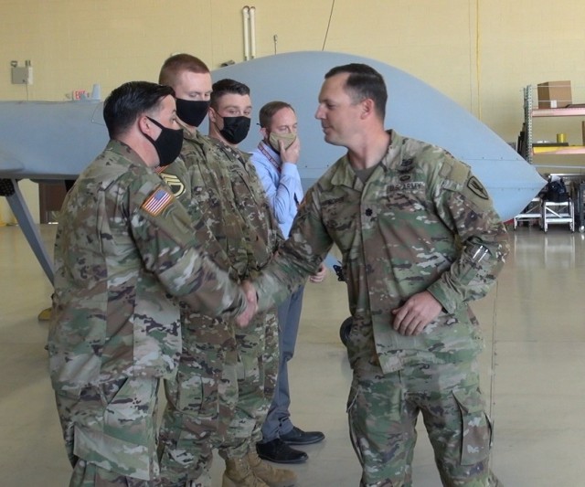 (right) Lt. Col  Jacob Roper,  Commander of the 2-13th Aviation Regiment presents coins to the crew of the Grey Eagle, Unmanned Aircraft System (UAS)  that surpassed 100,000 hours of flight time at a ceremony in Hangar 5 at Libby Army Airfield at Fort Huachuca, Ariz