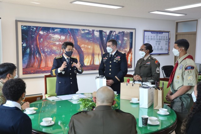 Nam-gu District Police Chief Kap Soo Yi speaks with Maj. Gabriel Bowns, Sgt. 1st Class Gisela Schilling and Azizi Wilkins about their acts of heroism that resulted in a burning building being evacuated with no casualties. Chief Yi presented the trio with traditional Korean gifts in recognition of their selfless acts.