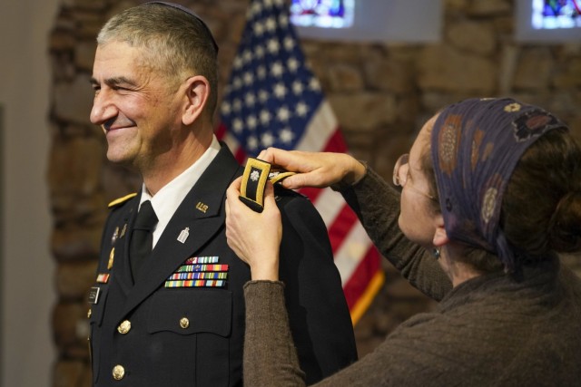 Dr. Amy Soussan places shoulder boards with the rank of colonel on Chaplain (Col.) Henry Soussan, U.S. Army Garrison Bavaria Deputy Garrison Chaplain, during his promotion ceremony at the Tower Barracks Chapel, Nov. 23, 2021. (U.S. Army photo by Julian Temblador / USAG Bavaria)