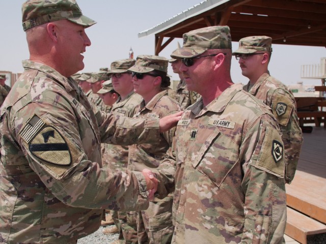 Col. Robert J. Kincaid Jr. presents Cpt. Sid Kidd (right) with a commanders coin. Kidd was among the five Soldiers who also deployed with the 111th Engineer Brigade in 2003.
