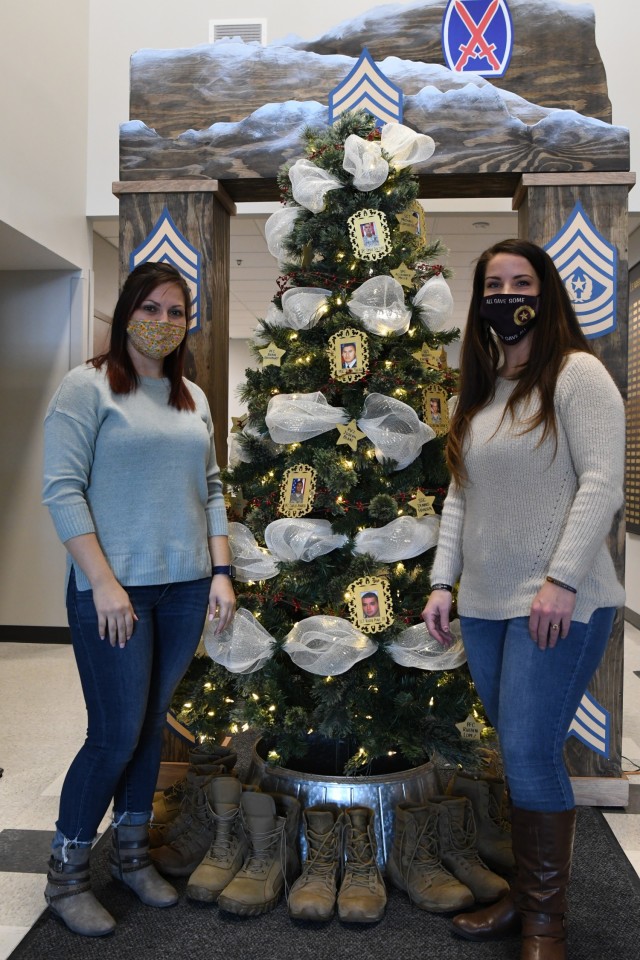 Tika Farless and Ashleigh Pursel Carlin decorate the Honor the Fallen holiday tree with photos and names of fallen 10th Mountain Division (LI) Soldiers at the entrance of the Noncommissioned Officer Academy on Nov. 29. This is the second year that trees have been placed on post as a reminder of the sacrifices made by Soldiers and to ensure Gold Star families that they remain in the hearts and minds of the Fort Drum community. (Photo by Mike Strasser, Fort Drum Garrison Public Affairs)