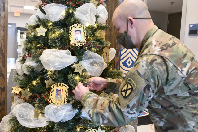 Command Sgt. Maj. Ronald Newman, Fort Drum Noncommissioned Officer Academy commandant places an ornament of a Soldier he knew on the Honor the Fallen holiday tree Nov. 29 at the NCOA. (Photo by Mike Strasser, Fort Drum Garrison Public Affairs)