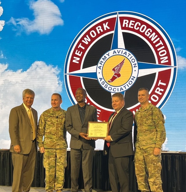 Stan Oliver, third from left, owner of DigiFlight Inc., and John Haeme, fourth from left, project lead/AH-64 Standardization Instructor Pilot, accept the Materiel Readiness Award on behalf of the Apache New Equipment Training team during the Army Aviation Association of America’s Joseph P. Cribbins symposium Nov.16. Looking on, from left, are retired Maj. Gen. Tim Crosby, president of AAAA; Lt. Gen. Thomas Todd, deputy commander for acquisition and systems management, Army Futures Command; and Maj. Gen. Todd Royar, commander of the Aviation and Missile Command. (Photo by Shannon Murphy)