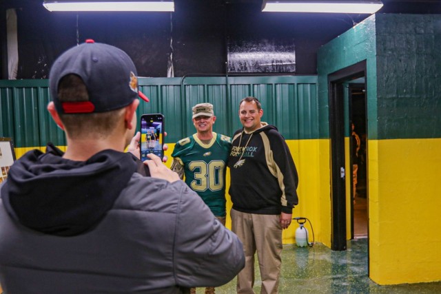 General Paul Funk II's son snaps a photo of Funk and Fort Knox Middle/High School football Coach Wes Arnold in the locker room before the final football game of the season October 29. The Fort Knox Eagles honored Funk, commanding general, U.S. Army Training and Doctrine Command, and former Eagle football star, with a jersey retirement ceremony during halftime of the final game of the 2021 season. Funk's former coaches surprised him by attending the leader's homecoming ceremony and he attributed his initial leadership training to his mentors. Funk's wife, youngest son, and other family members and friends were in attendance for the momentous occasion. (U.S. Army photo by Staff Sgt. Nicholas Brown-Bell)