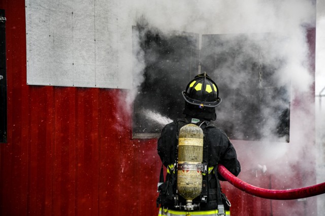A firefighter douses a class A fire through a window during a combined live fire training exercise at Humphreys Fire and Emergency Services training area Nov. 23, 2021.