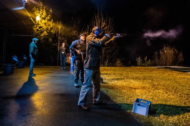 A shooter fires at a clay target.