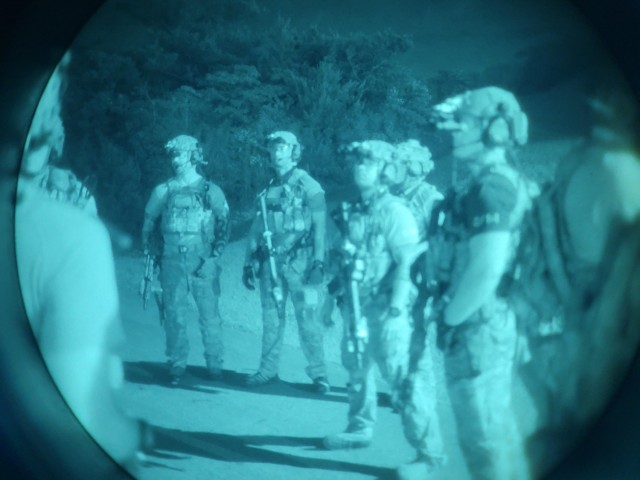 Green Berets and explosive ordnance disposal soldiers prepare to train for night direct action operations in Okinawa, Japan on May, 20, 2021. Soldiers are visible through a night-vision optic.

