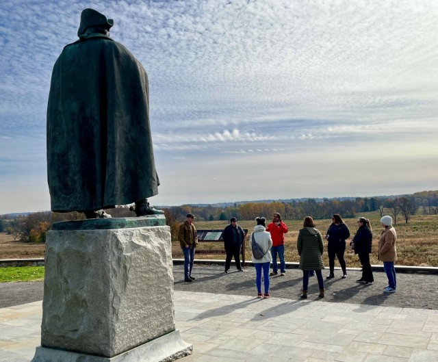 Mentors and Mentees for New Cumberland, Pennsylvania and the Washington Field Office gather around a statue of General Von Steuben to learn about his leadership styles and involvement with reshaping the Colonial Army. 