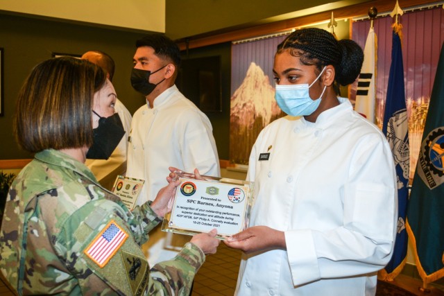 Col. Lisa Rennard, brigade commander, 403rd Army Field Support Brigade, presents a plaque to Spc. Anyona Barnes, administration non-commissioned officer in charge, Sustainer Grill, during a ceremony recognizing the Sustainer Grill as the best...