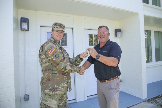 Maj. Jay Parsons, left, accepts keys to the revitalized Quarters 436 from LOGCAP Director of Operations and Maintenance Clint Easton during a ribbon-cutting ceremony Nov. 19, 2021. Representative of the 1950s-era construction still in use on U.S. Army Garrison-Kwajalein Atoll, the Navy-built quarters was refurbished with funding provided by Army Family Housing.