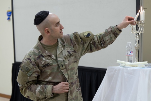 1st Lt. Jon C. Phoenix, a finance officer assigned to Task Force Spartan, lights the candle on a menorah during a celebration of the second night of Hanukkah at Camp Arifjan, Kuwait, on Nov. 29, 2021. Hanukkah, also known as the Festival of Lights, is an eight-day holiday that reaffirms the paragons of Judaism. Soldiers and members of the community were able to celebrate the holiday each night at the religious affairs center on the camp.