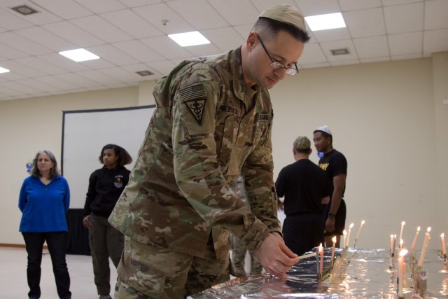 Maj. George E. Milevich, a pharmacist deployed with the 3rd Medical Command, 1st Theater Sustainment Command, lights a candle on a hanukkiah during a celebration of the second night of Hanukkah at Camp Arifjan, Kuwait, on Nov. 29, 2021. “Usually I celebrate it with my children, but this year, obviously being deployed I can’t do that,” the Rochester, N.Y., native said. “So I got do it with our Army family, which is great.”