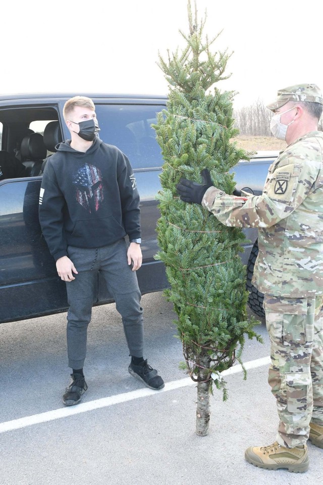 Pfc. Jason Barron, with D Company, 3rd General Support Aviation Battalion, 10th Aviation Regiment, 10th Combat Aviation Brigade, has a tree delivered to his car by Command Sgt. Maj. Mario Terenas, 10th Mountain Division (LI) senior enlisted adviser, on Dec. 4 during the Trees for Troops event. (Photo by Mike Strasser, Fort Drum Garrison Public Affairs)