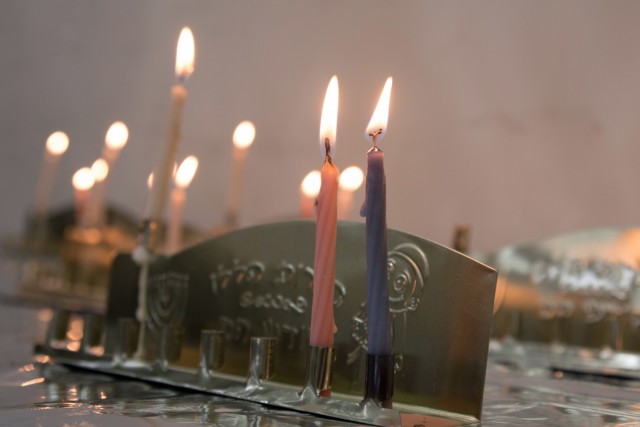 Candles in hanukkiahs burn in the background as Soldiers and civilians celebrate the second night of Hanukkah at Camp Arifjan, Kuwait, Nov. 29, 2021. “The point of that is to share the light that comes from here,” said Spc. Armon Chaim, a...