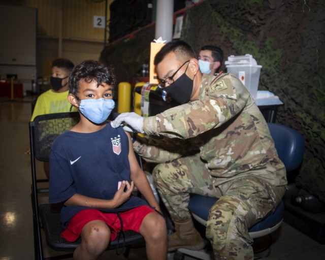 Pvt. Eduardo Toruno administers a vaccine to Kingston Dye at the Brooke Army Medical Center COVID-19 Vaccine Site, Fort Sam Houston, Texas, Dec. 3, 2021. The Vaccine Site is closing after nearly a year of operations due to the wide availability of the vaccine within the community and subsequent decline in demand at the site. (U.S. Army photo by Jason W. Edwards)