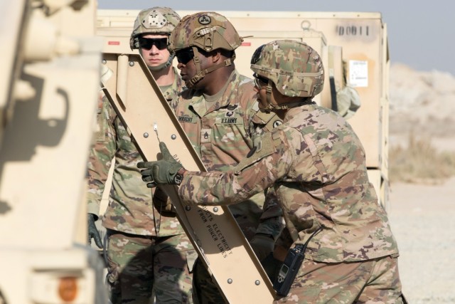 Staff Sgt. Carlos S. Wright and Master Sgt. Vantha Chhim set up a ladder outside of an M1087 Expandable Van Shelter during a tactical action center displacement training exercise at Camp Arifjan, Kuwait, on Nov. 27, 2021. The shelters are structures mounted to medium tactical vehicles designed to provide mobile workspace for the provision of logistics support. The “Spears Ready” Soldiers have been deployed since August staffing the 1st Theater Sustainment Command’s operational command post.