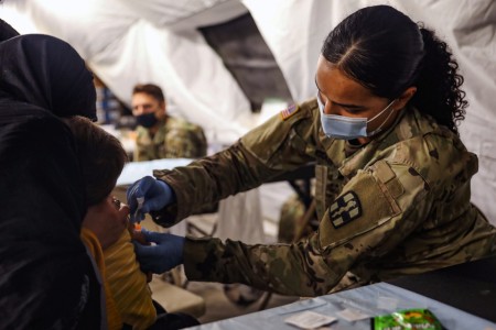 Army Spc. Jessica Collet, a practical nursing specialist, administers a vaccine to an Afghan child while supporting Operation Allies Welcome at Fort Bliss’ Doña Ana Complex in New Mexico, Sept. 16, 2021.
