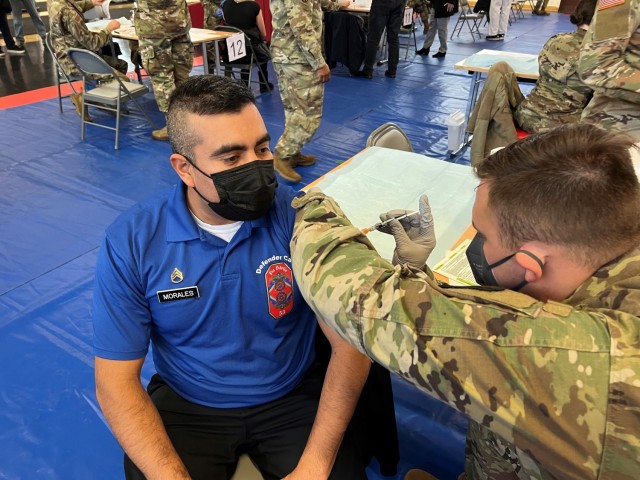 PFC Timothy Puckett, 512th Field Hospital, administers a COVID-19 booster shot to Staff Sgt. Jorge Morales, 55QM, 16th Sustainment Brigade, during a Booster Rodeo at Kleber Gym, Kaiserslautern, Germany, on December 8, 2021. Soldiers from the 30th...