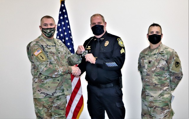 Sgt. Kevin Eckelberg with the Directorate of Emergency Services Police Department receives a Commander's Coin of Excellence on Dec. 2, 2021, from Fort McCoy (Wis.) Garrison Commander Col. Michael Poss as part of the Garrison Command Team who...