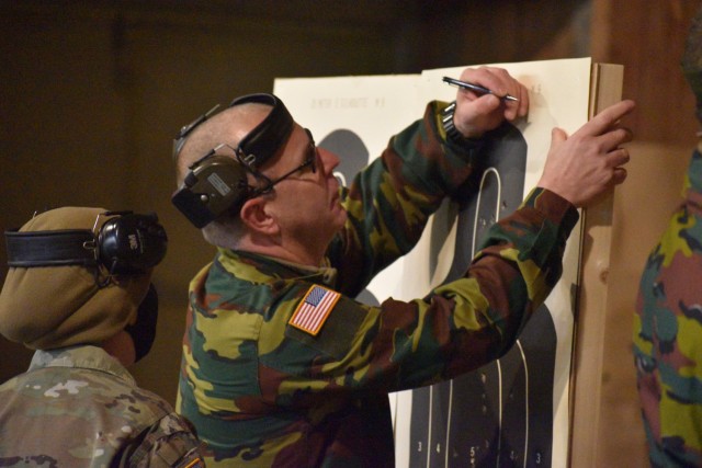 Belgian armed forces 1st Sgt. Kris Weemaes, right, instructor with the Belgian military police group training unit, marks where he hit the paper as Sgt. 1st Class Jerri Lynn Daniels, center right, U.S. Army Garrison Benelux – Brussels provost...