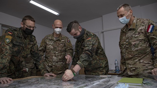 Netherlands Army and German Army soldiers assigned to enhanced Forward Presence Battle Group Lithuania examine their topographical map at Bemowo Piskie Training Area, Poland, Dec. 7, 2021. The purpose of this command post exercise was to see multiple countries practice in a simulated environment together, rehearsing NATO collective defense in a crisis response scenario. (U.S. Army photo by Spc. Jameson Harris)