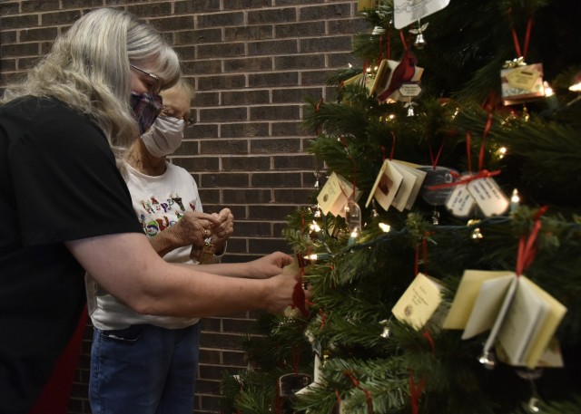 Survivor Outreach Services Coordinator Jody Carmack (left) assists survivor Lois Robbins as she hangs ornaments on the Angel Bell Remembrance Tree in the Army Community Service lobby. More than 700 ornaments have been designed and created since...