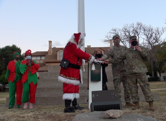 Santa Claus, Heidi Malarchik, Deputy to the Commander, U.S. Army Garrison-Fort Huachuca, Col. Jarrod Moreland, Commander, U.S. Army Garrison-Fort Huachuca, and Maj. Gen. Anthony Hale, Commanding General, U.S. Army Intelligence Center of Excellence, and Fort Huachuca flip the switch to officially mark the holiday season on Friday, Dec. 10, 2021, on Brown Parade Field at Fort Huachuca, Ariz.