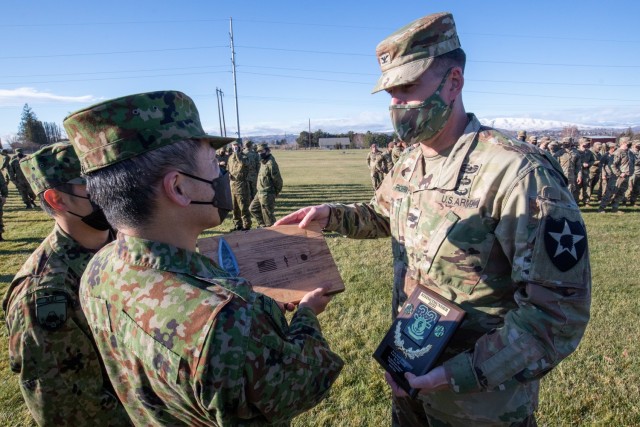 Army Col. Chad Roehrman, commander of 2nd Stryker Brigade Combat Team, 7th Infantry Division, presents a plaque to Col. Koichi Koba, commander of the 32nd Infantry Regiment, Japanese Ground Self-Defense Force, to commemorate the end of a weeks-long training event during training exercise Rising Thunder on December 14, 2021 at Yakima Training Center, Wa.

  - Photo courtesy of Sgt. Ayato Takai, Japanese Ground Self-Defense Force